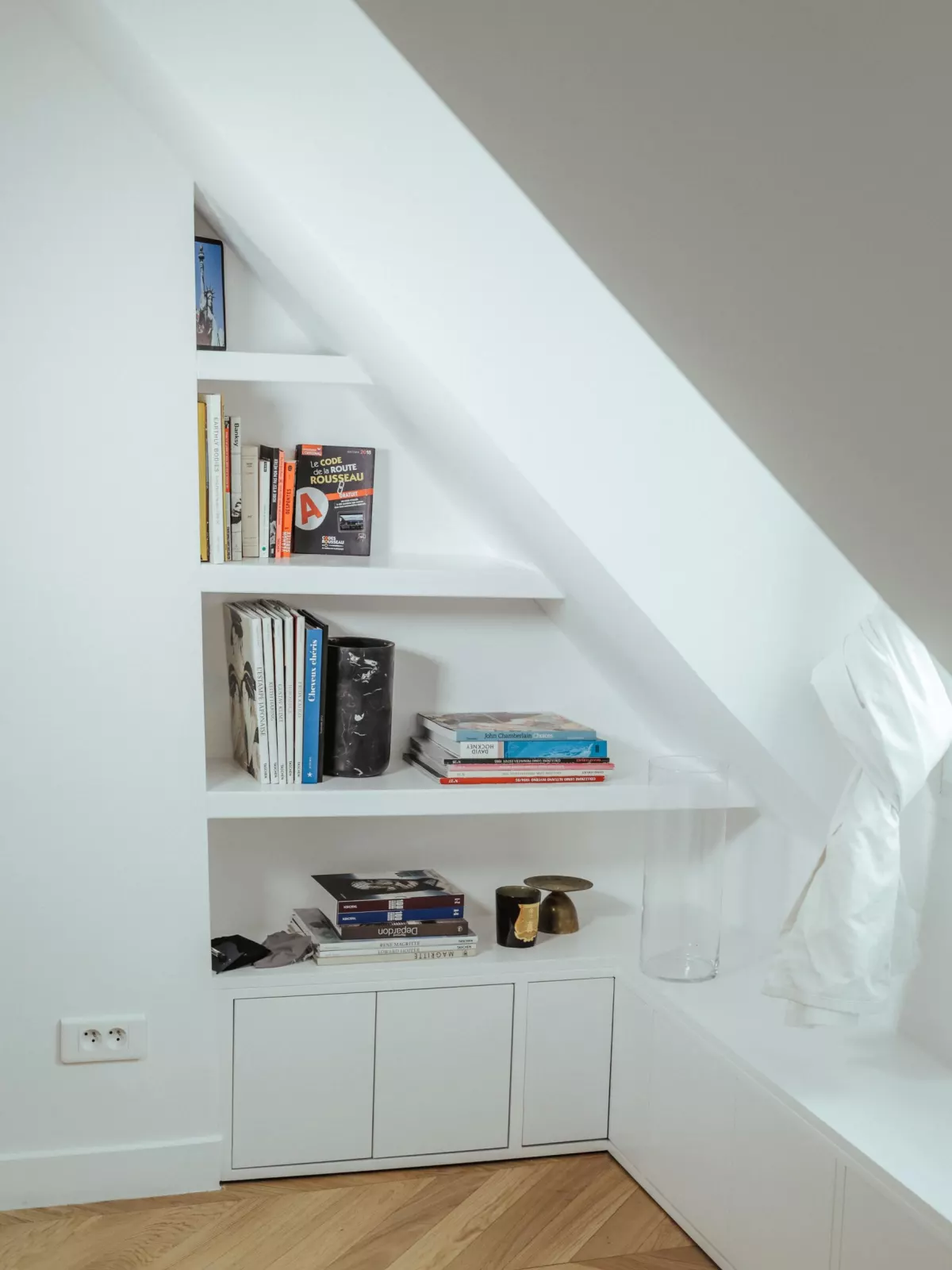 Biblioth&egrave;que sur mesure install&eacute;e sous une pente de toit, avec rangements bas ferm&eacute;s