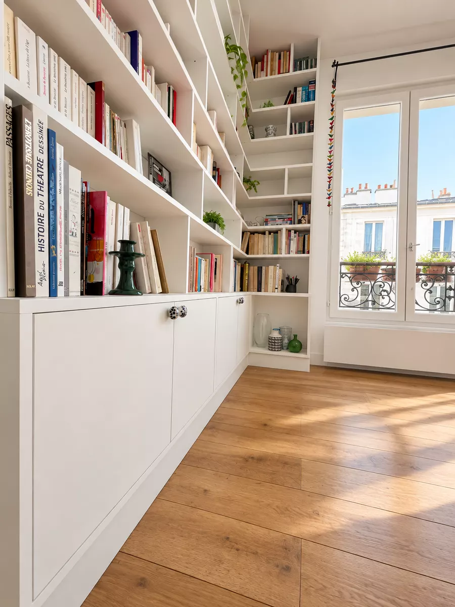 Bibliothèque blanche installée de part et d'autre d'une fenêtre parisienne