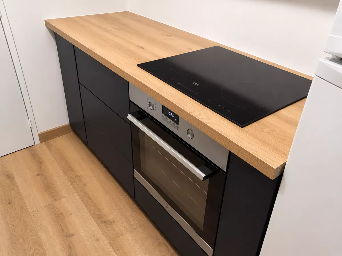 Cuisine sur mesure noire avec four encastré et plan de travail en bois