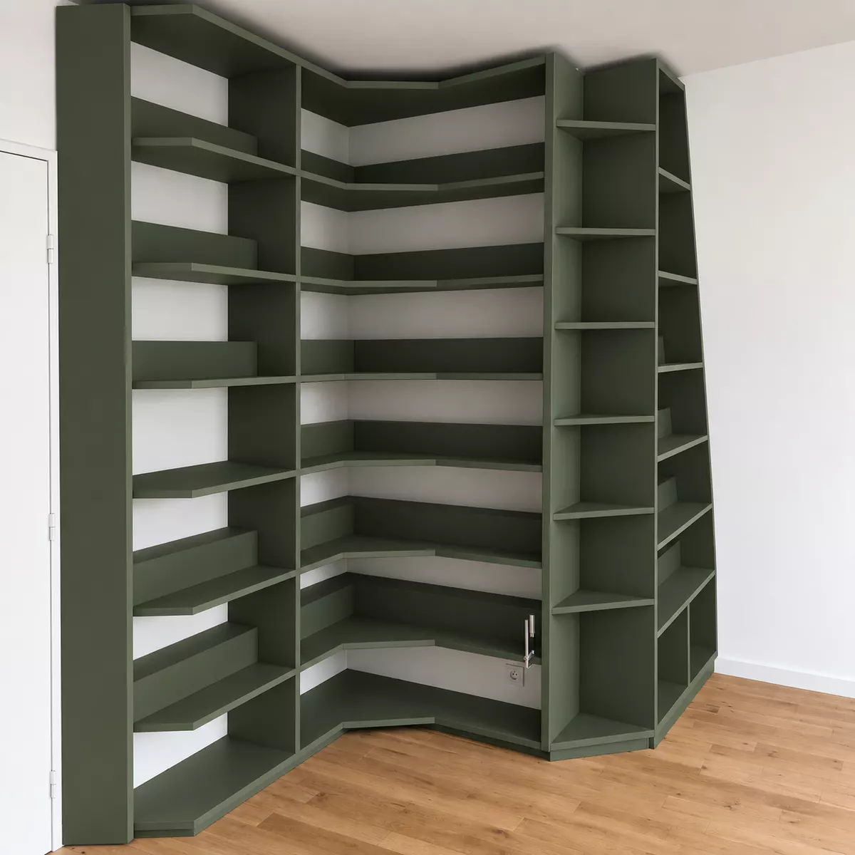 Biblioth&egrave;que d&rsquo;angle vert fonc&eacute; montant toute la hauteur du mur